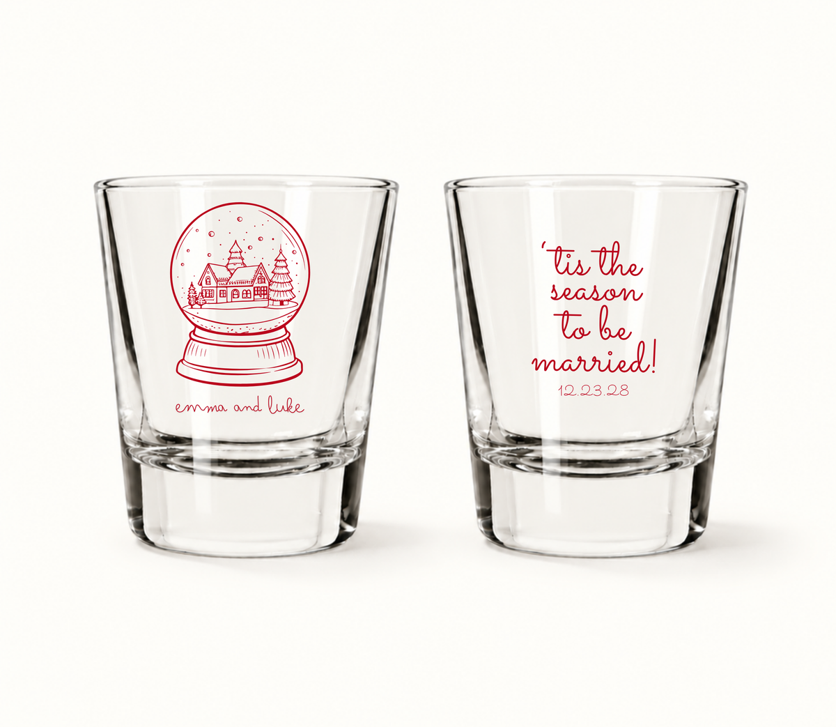 Personalized Tis The Season Christmas wedding shot glasses featuring a snow globe winter village, custom couple names, and wedding date.