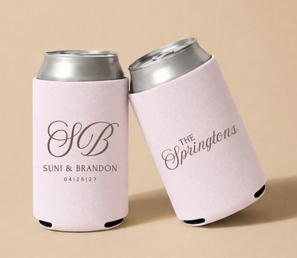 Pink personalized foam wedding can coolers featuring an ornate vintage monogram with initials SB family name The Springtons, and wedding date April 25, 2027.
