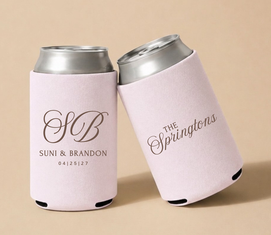 Pink personalized foam wedding can coolers featuring an ornate vintage monogram with initials SB family name The Springtons, and wedding date April 25, 2027.
