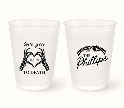 Personalized Love You to Death frosted Halloween wedding cups featuring black skeleton hands forming hearts, The Phillips last name, and wedding date 10.31.28.