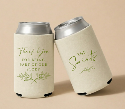Cream personalized wedding can coolers featuring botanical olive branch artwork, heartfelt thank you message, custom family name The Saints, and wedding date.
