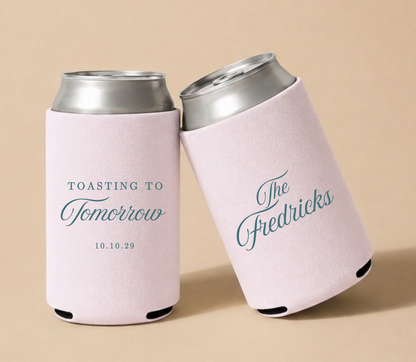 Blush pink personalized foam wedding can coolers featuring "Toasting to Tomorrow" design, custom Fredericks family name, and wedding date October 10, 2029.

