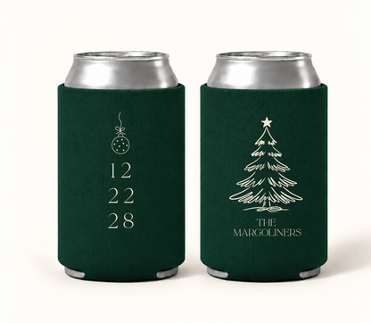 Personalized emerald green Christmas wedding can coolers featuring ivory Christmas tree artwork, hanging ornament, custom family name, and wedding date.