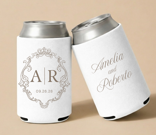 White personalized wedding can coolers featuring an elegant ornamental monogram frame with custom initials A and R, wedding date, and Amelia and Roberto names.
