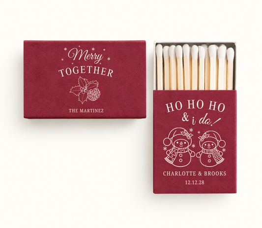 Personalized red Merry Together Christmas wedding matchboxes featuring snowman artwork, holly and pinecone details, Charlotte and Brooks names, and wedding date.