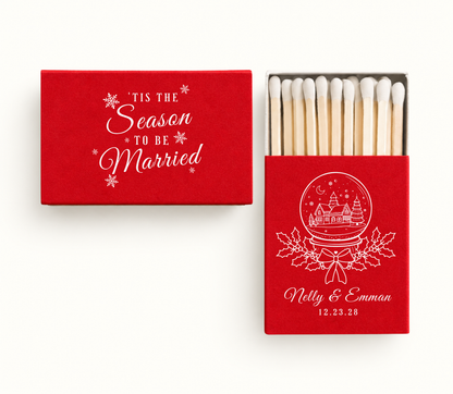Personalized red 'Tis The Season To Be Married Christmas wedding matchboxes featuring white snow globe artwork, holly details, Nelly and Emman names, and wedding date.