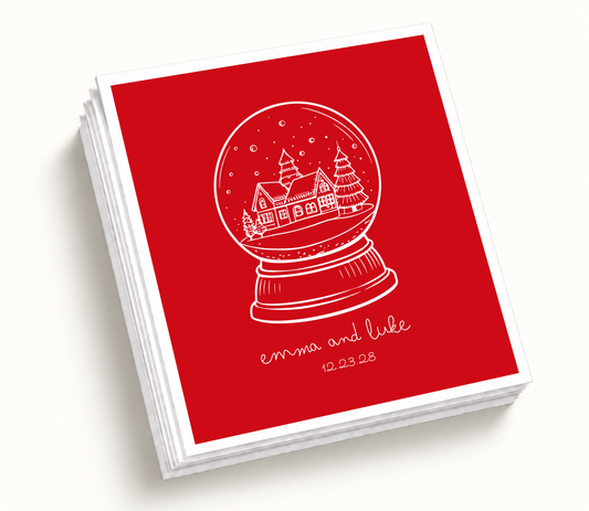 Personalized red Christmas snow globe wedding napkins featuring white winter cabin illustration, snowy landscape artwork, custom couple names, and wedding date.