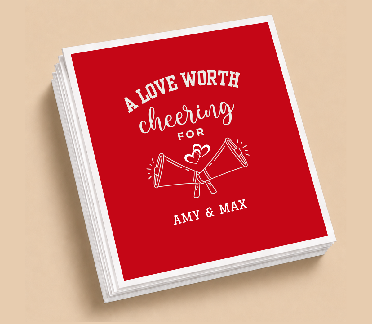 Personalized A Love Worth Cheering For football wedding napkins featuring crossed megaphones, heart details, white lettering, and a red background.