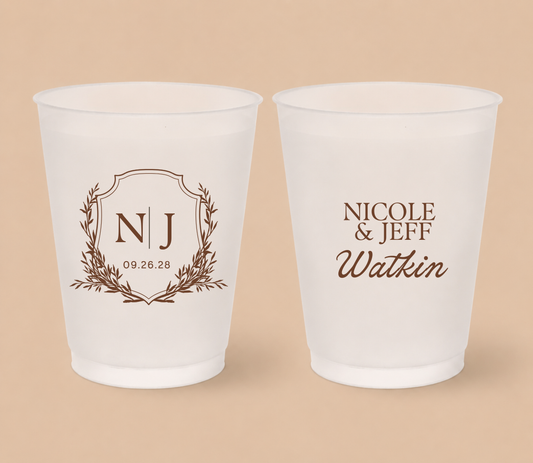 White frosted wedding cups featuring an elegant crest monogram with initials NJ, custom couple names Nicole and Jeff Watkin, and wedding date.