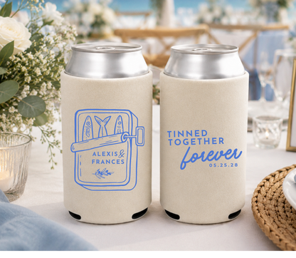 Two can coolers with personalized designs on a table with a wedding setting in the background.