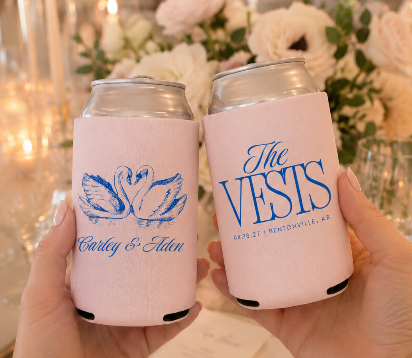 Two can coolers with personalized swan designs on a table with flowers and candles.