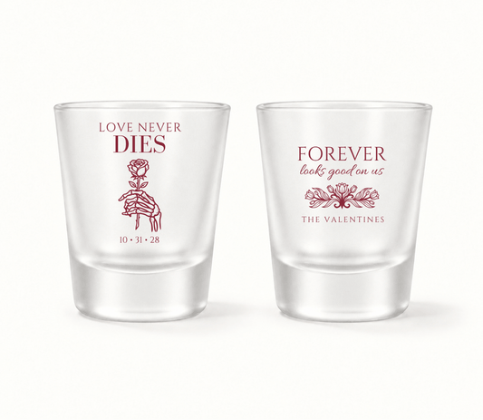 Personalized clear Love Never Dies wedding shot glasses featuring burgundy skeleton hand holding a rose, Forever Looks Good on Us wording, The Valentines surname, and wedding date 10.31.28.

