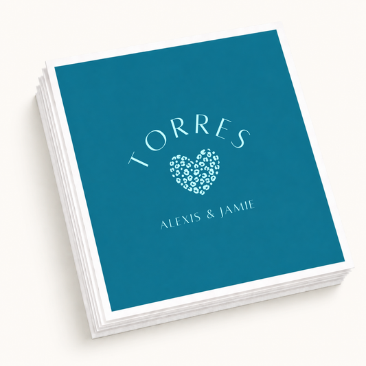 Personalized teal wedding cocktail napkins featuring a light blue leopard print heart, Torres family name, and Alexis and Jamie couple names.
