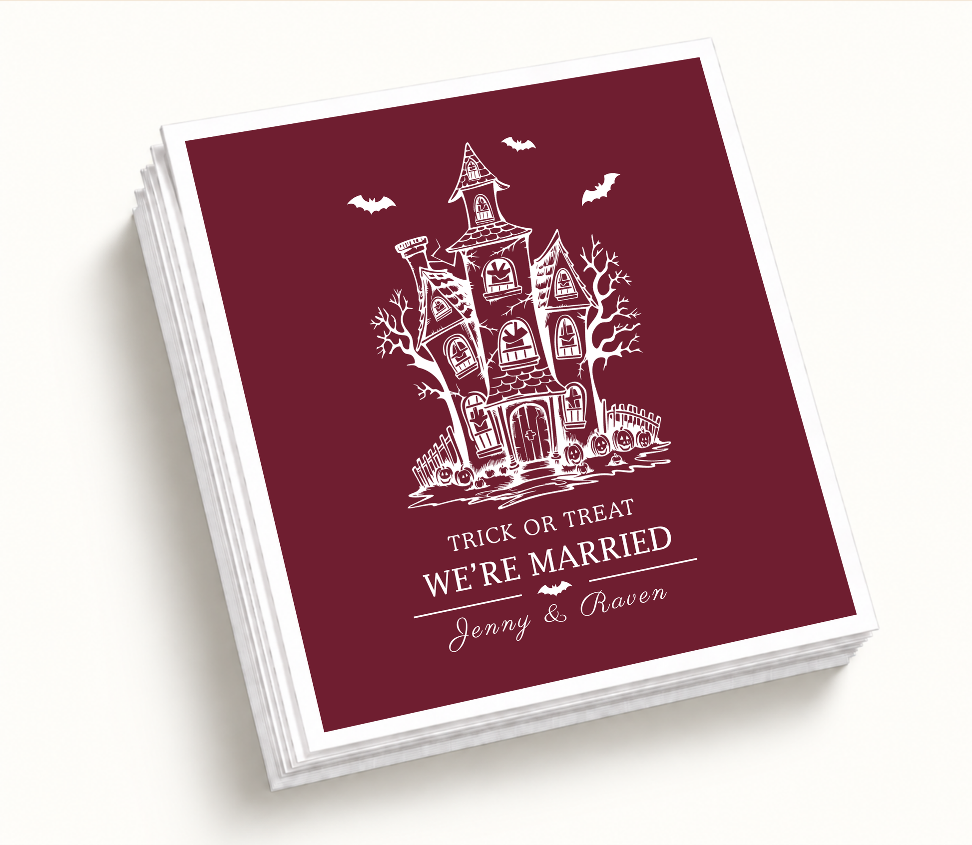 Personalized Trick or Treat We’re Married burgundy Halloween wedding cocktail napkins featuring a white haunted house, bats, pumpkins, and custom couple names.