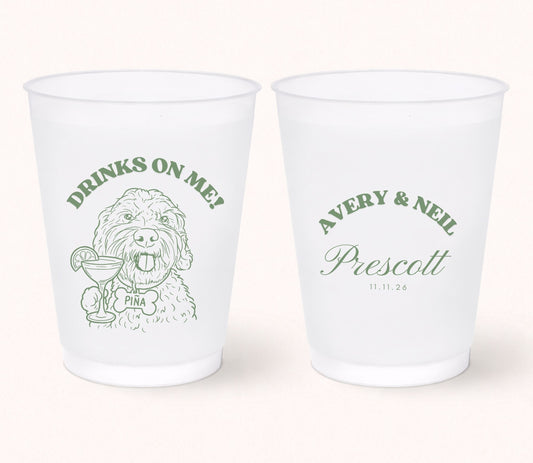 Two personalized frosted wedding cups featuring a custom dog portrait holding a cocktail with the pet name Pina on the front and Avery & Neil Prescott with the wedding date 11.11.26 on the back in sage green print.
Personalized frosted wedding cup featuring a custom dog portrait with a signature cocktail illustration.
Custom pet portrait wedding cup with dog artwork, personalized names, and wedding date.