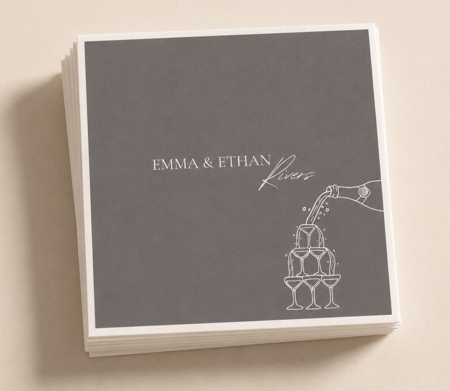 Personalized champagne tower wedding napkins with white pour artwork and custom couple names on charcoal gray napkins