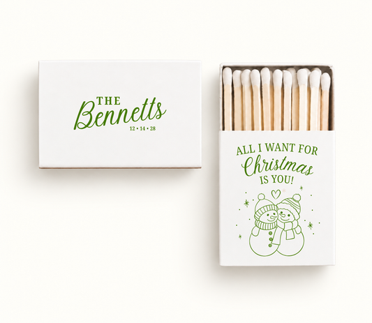 Personalized white All I Want for Christmas wedding matchboxes featuring green snowman couple artwork, The Bennetts name, and wedding date.