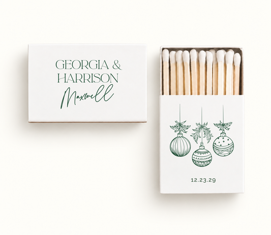 Personalized white Christmas ornament wedding matchboxes featuring green hanging ornament artwork, Georgia and Harrison names, and wedding date.