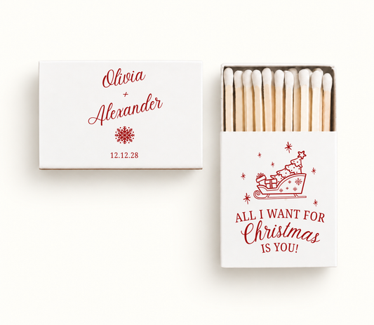 Personalized white All I Want for Christmas wedding matchboxes featuring red Christmas sleigh artwork, Olivia and Alexander names, snowflake, and wedding date 12.12.28.