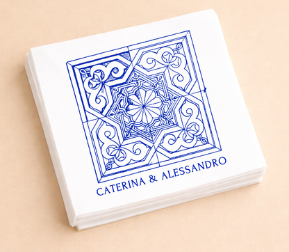 White personalized cocktail napkins featuring intricate Mediterranean blue tile artwork with custom names Caterina and Alessandro.