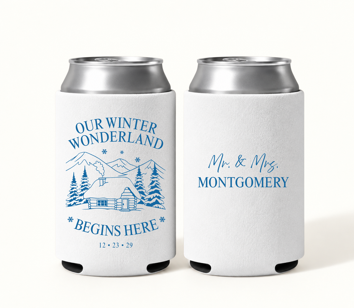 Personalized white Winter Wonderland wedding can coolers featuring blue snowy mountain cabin artwork, Our Winter Wonderland Begins Here wording, wedding date, and Mr. and Mrs. Montgomery design.