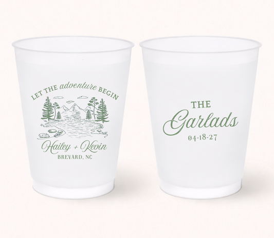 Two personalized frosted wedding cups featuring a scenic mountain landscape with the phrase "Let the Begin," Hailey and Kevin, Brevard, North Carolina on one side and "The Garlads" with the wedding date 04.18.27 on the reverse.
Personalized mountain wedding frosted cup featuring a scenic forest and river illustration.
Adventure wedding drink cup with custom names, mountain artwork, and wedding date.