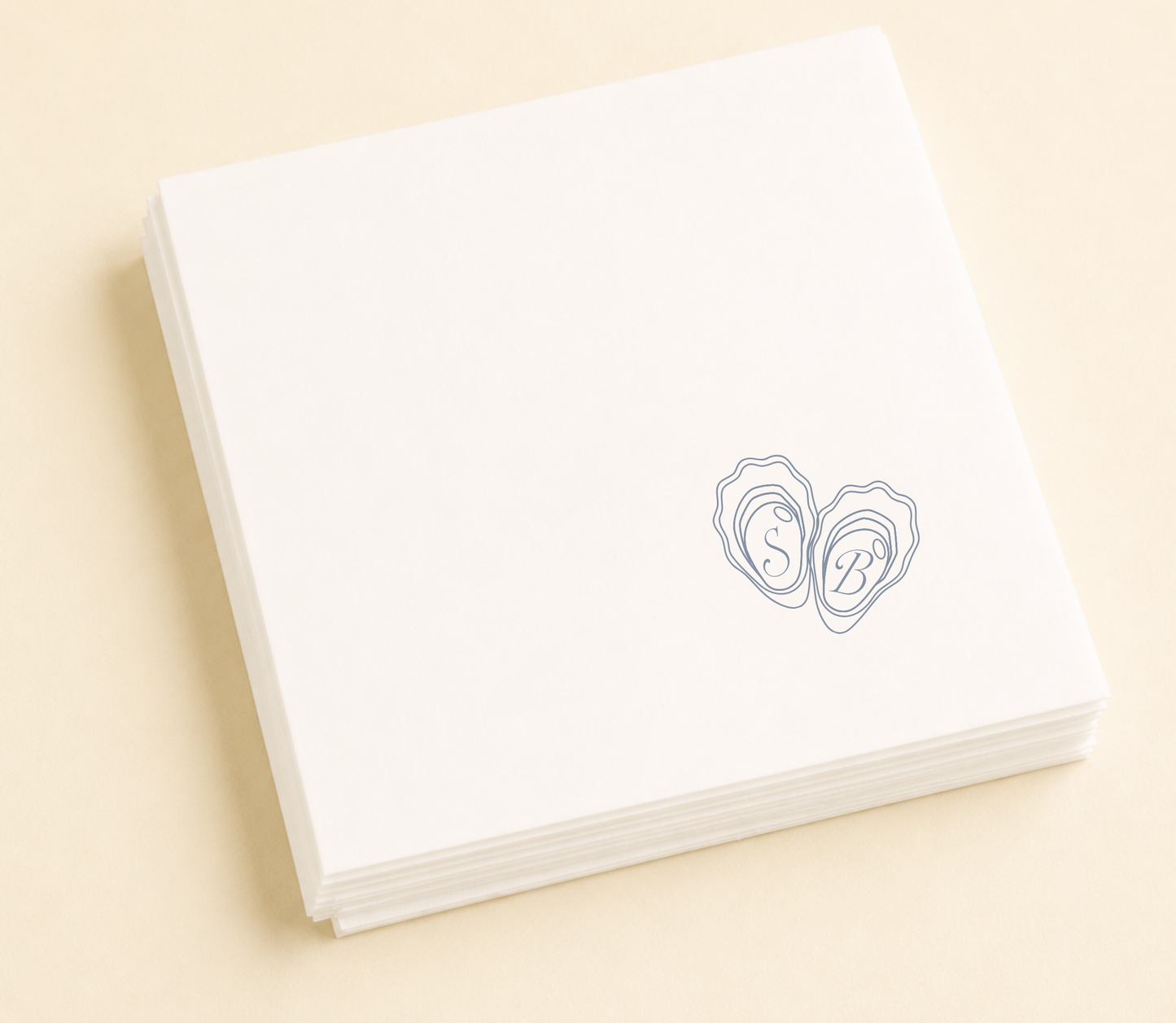 white napkins with  the couples initials and some oyster shells design on a beige background