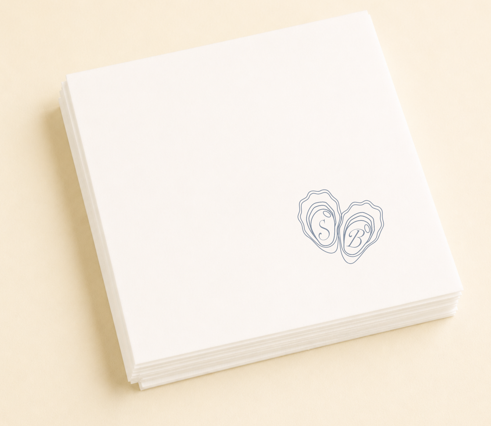white napkins with  the couples initials and some oyster shells design on a beige background