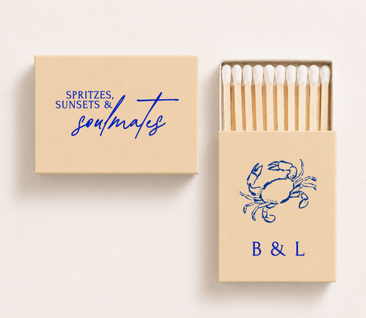 Personalized coastal wedding matchboxes featuring a blue crab illustration, custom initials, and seaside-inspired wedding wording.