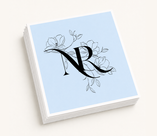 Personalized floral monogram wedding cocktail napkins featuring magnolia-inspired botanical artwork and custom intertwined initials.