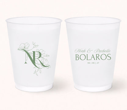Two personalized frosted wedding cups featuring a floral monogram "NR" on one side and Noah & Rachelle Bolaros with the wedding date 06.06.27 printed in elegant sage green on the reverse.
Personalized wedding frosted cup featuring a floral monogram initial and elegant botanical artwork.
Custom monogram wedding drink cup with personalized couple names and wedding date.